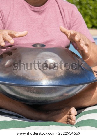 Man playing a percussion instrument. Hangpan or handpan of golden color. Musical instrument.