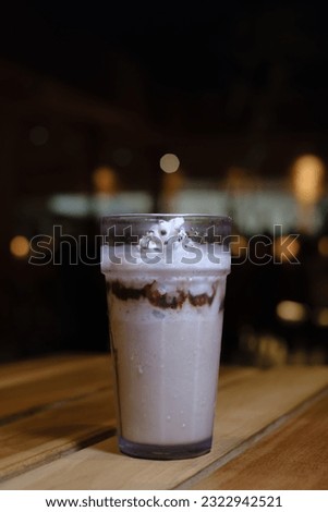 Portrait or vertical shot of a glass of Iced Chocolate with Whip Cream on a wooden table with bokeh or blurred background. Selective focus.