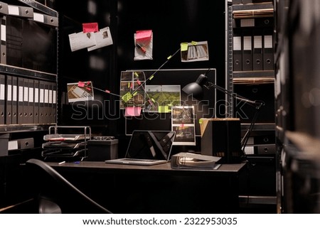 Empty dark police detective room with murder case investigation process on board. Suspect photographs connected with clues hanging on wall and file folders on racks in investigator agency office Royalty-Free Stock Photo #2322953035