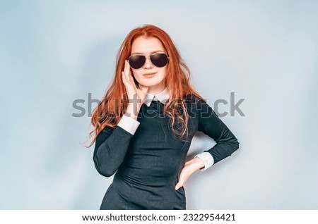Stylish woman holds black glasses with hand. Black strict dress with a white collar. Sunglasses