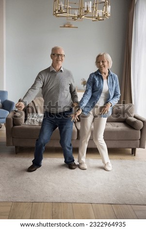 Cheerful active old wife and husband have fun in living room together move to rhythm listen favorite music, happy overjoyed senior spouses dance enjoy leisure weekend at new home, feel love to life Royalty-Free Stock Photo #2322964935