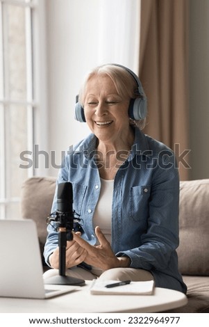 Happy 65s woman in headphones speaks into microphone lead on-line stream using wireless computer, record voice, teach audience, share experience to subscribers. Live stream event, hobby on retirement