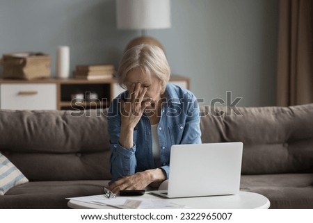 Stressed old woman sit on couch feels worried about money problem, suffer from lack of finances, check domestic expenditures, shocked about eviction notice. Financial crisis, insolvency, small pension Royalty-Free Stock Photo #2322965007