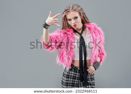 Glam rock style. Portrait of an attractive teenage girl in fashionable bright clothes on a gray studio background with copy space. Glamorous rock star girl.