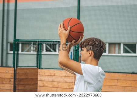 Young talented basketball player is shooting hoops on his outdoor court and training for future games and tough situations. Preparing for the season. Shooting the basket.