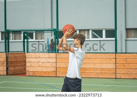 Young talented basketball player is shooting hoops on his outdoor court and training for future games and tough situations. Preparing for the season. Shooting the basket.