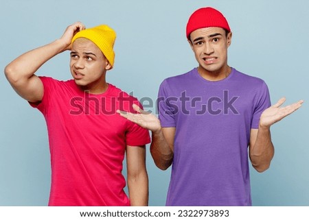 Young confused puzzled couple two friends men wear casual clothes together shrugging shoulders looking puzzled spread hands look aside scratch head isolated on pastel plain light blue cyan background Royalty-Free Stock Photo #2322973893