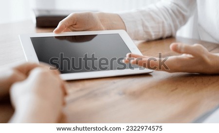 Contract papers are lying at the wooden desk while business people discussing something at the wooden desk at the background. Teamwork, partnership, contract signing concept