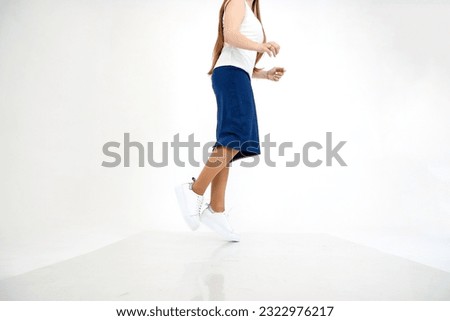 Beautiful white sneakers and woman legs in the studio on white background. Fashionable shooting of young girl with beautiful legs