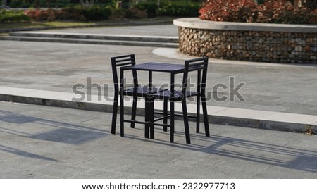 a black chair to seat two people, this chair is in an outdoor setting, guests can order food and sit on this chair.