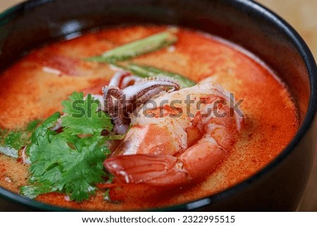 Experience the tangy and creamy delights of Tom Yum Soup. Indulge in succulent shrimp and tender squid, immersed in Thai flavors. A taste of Thailand's culinary magic in every bowl. Royalty-Free Stock Photo #2322995515