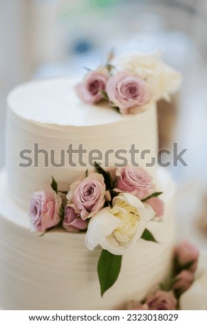 Creamy white wedding cake with flowers. Pink roses. Picture for a menu or confectionery catalog, restaurant, candy bar.
