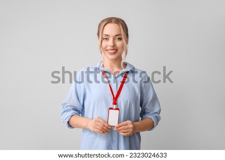 Young woman with blank badge on grey background
