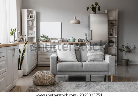 Interior of light kitchen with stylish fridge, counters, sofa and shelving units