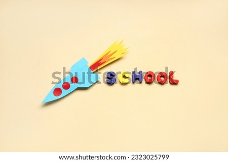 Paper rocket with word SCHOOL on beige background