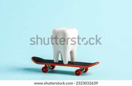 White human tooth model riding on skate on blue background. 