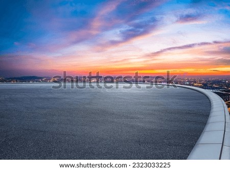 Round asphalt road and city skyline with colorful sky clouds at sunset