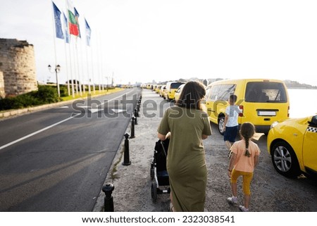 Mother with kids and local taxi on a street in Nessebar, Bulgaria.