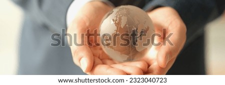 Hands of businessman in suit holding glass globe of earth closeup