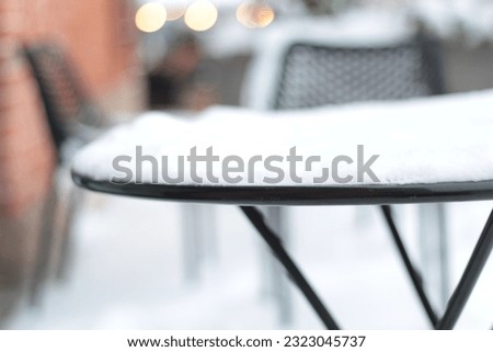 The first white fluffy snow on the table and chairs. Fabulous winter. Christmas time. Winter storm covers the deck and outdoor furniture