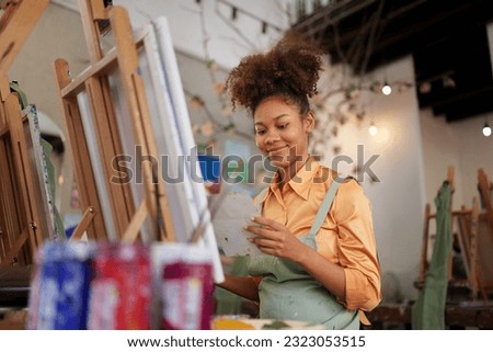 Beautiful American African artist woman painting in art studio at the university classroom
