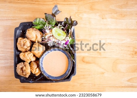 Capture the essence of Japanese cuisine with crispy karaage chicken on a rustic wooden table. A mouth-watering dish perfect for food blogs, menus, and designs.