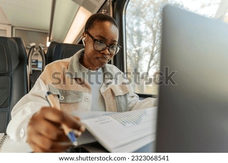 Modern business woman in the train traveling to work. Young woman writing down in notebook. Modern and fast travel concept.