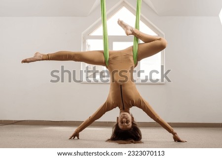 Caucasian woman doing air yoga exercises with fabric indoors