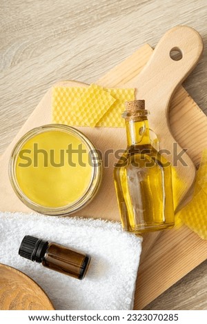 Homemade beeswax wood treatment polish, restore natural wood furniture, plates, cutting boards. Beeswax, olive oil and essential oil, soft cloth and mixture in glass jar.  Royalty-Free Stock Photo #2323070285