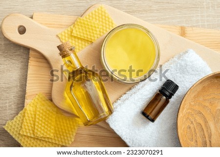 Homemade beeswax wood treatment polish, restore natural wood furniture, plates, cutting boards. Beeswax, olive oil and essential oil, soft cloth and mixture in glass jar.  Royalty-Free Stock Photo #2323070291