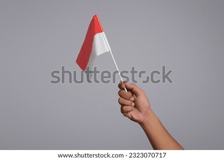Close up hands waving the red and white flag as a symbol of the Indonesian flag and copy space isolated on gray background. 17 August Indonesia independence day concept