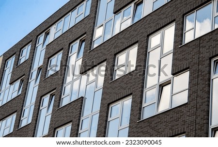 The facade is made in the form of geometric shapes. Tetris-like windows. Gray facing brick. Elements of modern architecture.