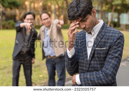 A young man feels depressed after being made fun of or being mocked by his colleagues. Feeling ashamed and ostracized. Possible racial discrimination. Royalty-Free Stock Photo #2323105757