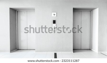 Elevators door closed in the hallway condominium. Light grey interior building with metal lifts, residential and commercial service. Architecture structure, elevation concept. Monotone color. Nobody.