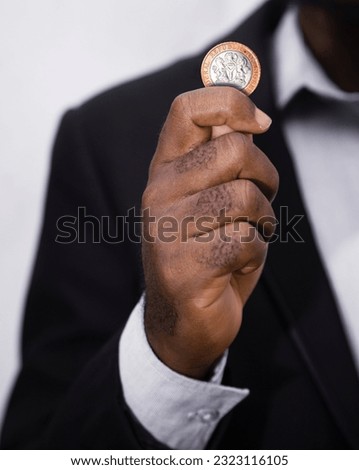 Businessman in suit holding 2 Nigerian naira coin. Hand holding coin