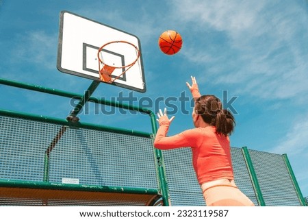 Female basketball player about to throw at the hoop. Outdoors in the sun