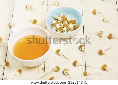 cup of herbal tea and dried chamomiles on rusty wood table