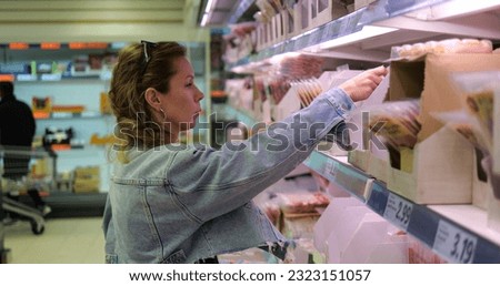 Shopping woman select precooked pre-sliced meat product for breakfast sandwich. Female buyer among vast selection of stacked plastic packs in grocery discount retailer store. High quality photo