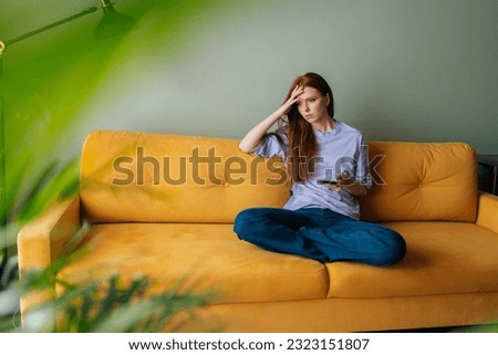 Portrait of pensive thoughtful young woman holding smartphone looking away lost on sad thoughts waiting first step from man, call or text message or date invitation from boyfriend feels jealousy. Royalty-Free Stock Photo #2323151807