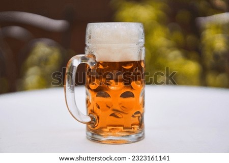 Close up picture on traditional shape mug of czech pale lager beer, the best beer in the world, amber color and rich white foam, on the table in the beer garden or outside in pub in hot summer evening