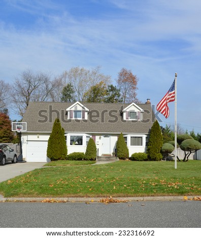 American flag pole suburban cape cod style home autumn fall day residential neighborhood blue sky clouds USA