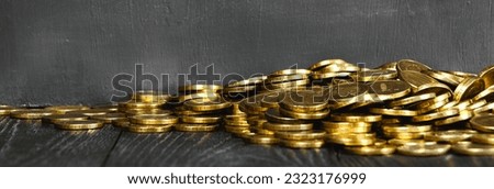 Gold coins on a wooden table banner. Money on a black background.Copy space.Treasure Hunt.Chalk rubbed out on blackboard. Chalkboard background.Black stone background.