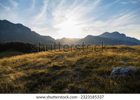 Wonderful autumn landscape in mountains. Grassy field and rolling hills. Sunset. Royalty-Free Stock Photo #2323185337