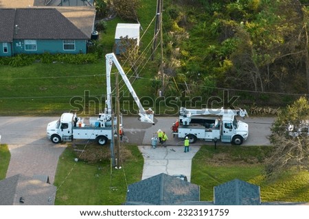 Electrical service company restoring power repairing damaged power lines after hurricane Ian in Florida suburban area Royalty-Free Stock Photo #2323191759