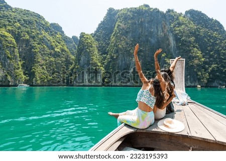 Group of Young Asian woman friends sitting on wooden boat passing tropical island beach in sunny day. Attractive girl enjoy outdoor lifestyle travel ocean on summer holiday vacation at Krabi, Thailand Royalty-Free Stock Photo #2323195393