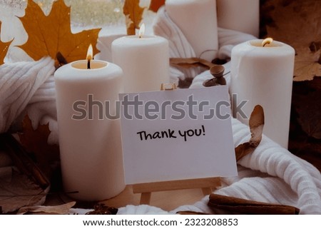 THANK YOU text greeting card concept Celebrating thanksgiving autumn holidays at cozy home on the windowsill Hygge aesthetic atmosphere Autumn leaves spices and candle on knitted white sweater in warm