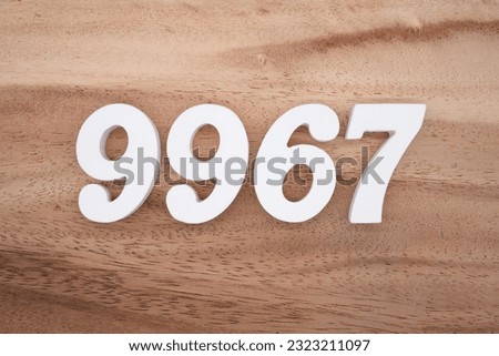 White number 9967 on a brown and light brown wooden background.