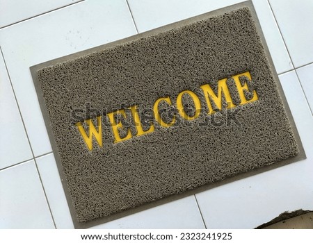Selective focus. The doormat is made of synthetic material with the word welcome screen printed.