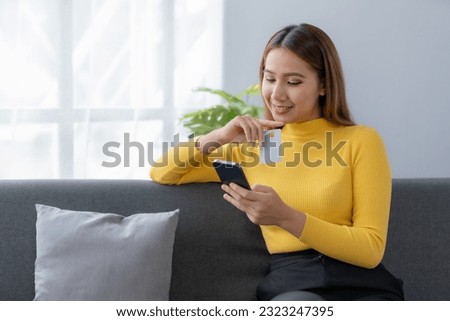 Young Asian Woman Using Smartphone for Online Shopping at Home. Asia female enjoying the convenience of online shopping from the comfort of her home.