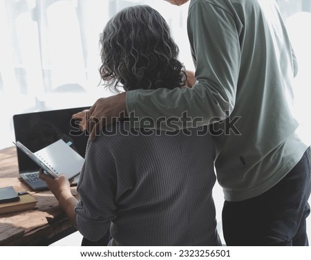 Embraced mature couple surfing the Internet on laptop at home